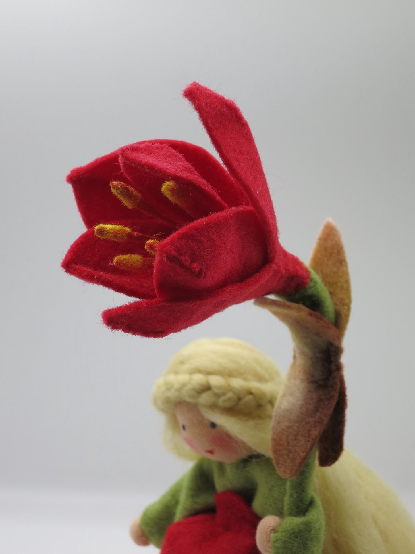 Detailaufnahme der dunkelroten Amaryllis-Filzblüte mit gelben Staubgefäßen am handgefertigten Blumenkind.