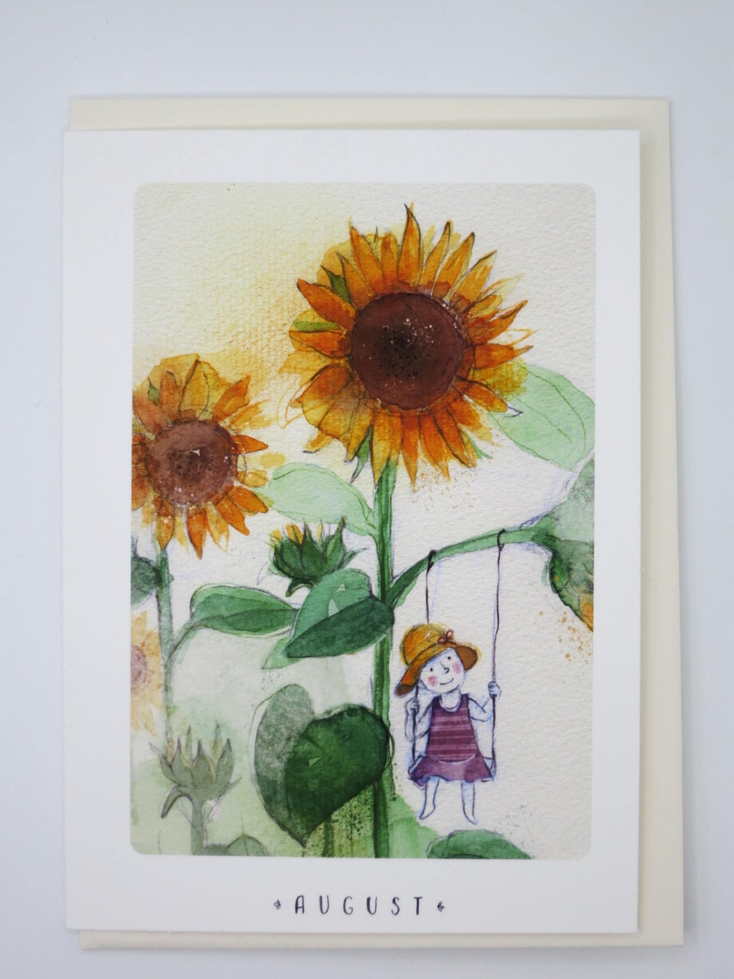 Waldorf Doppelkarte August von Stefanie Messing: Maedchen mit Sonnenhut schaukelt zwischen Sonnenblumen