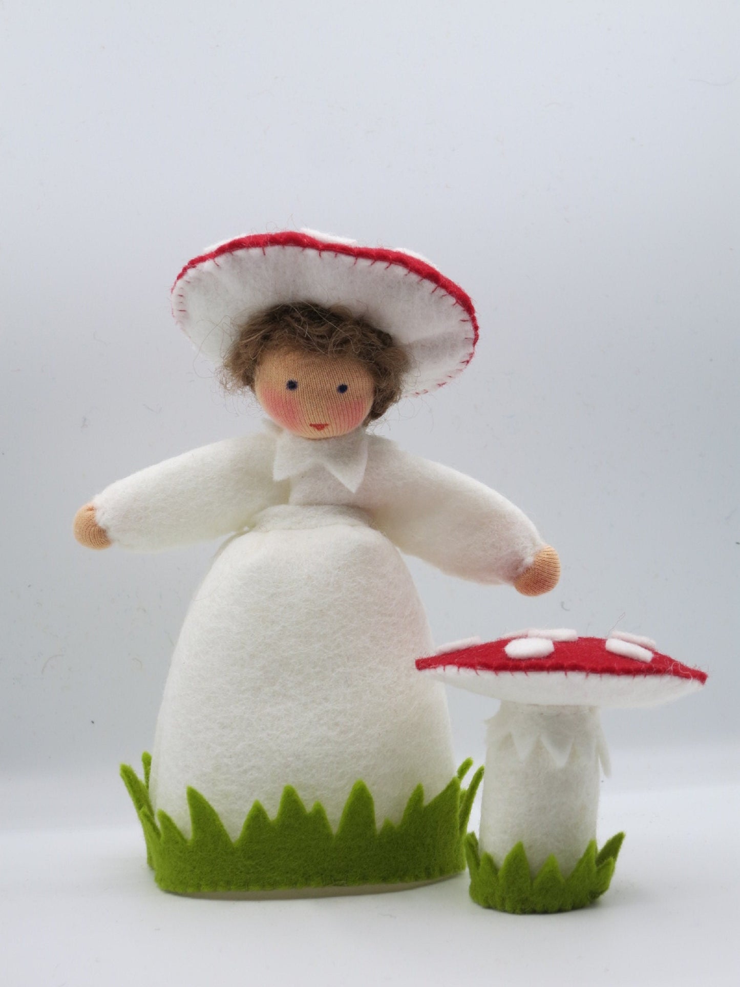 Handgefertigtes Fliegenpilz-Blumenkind aus Wollfilz mit weißem Gewand, Pilzhut und rotem Fliegenpilz für den Waldorf-Herbsttisch.