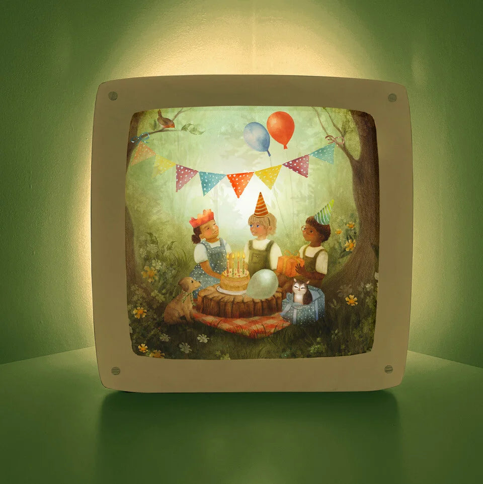 Toverlux Motiv Geburtstagspicknick MO185: drei Kinder mit Papierkrone und Partyhüten feiern im Wald an einem Baumstumpf mit Geburtstagstorte und Kerzen, Wimpelkette und Luftballons, Hund und Katze im Geschenkkarton, rot karierte Picknickdecke, Illustration von Bijdehansje, für den Geburtstagstisch und die Toverlux Lampe