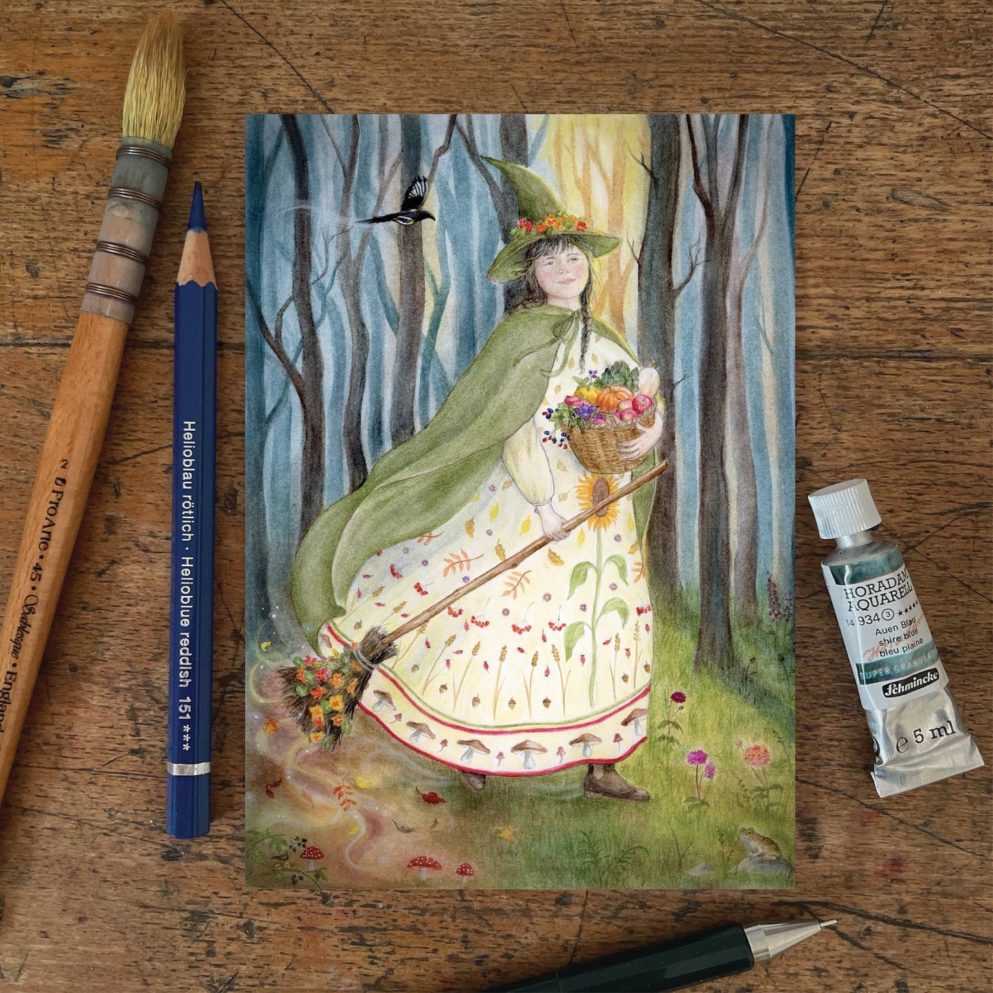 Herbst Postkarte Herbstanfang PKHE238: Herbstfigur mit Spitzhut Umhang Fruechtekorb und Besen Aquarell von Mhairi Hellbrandt