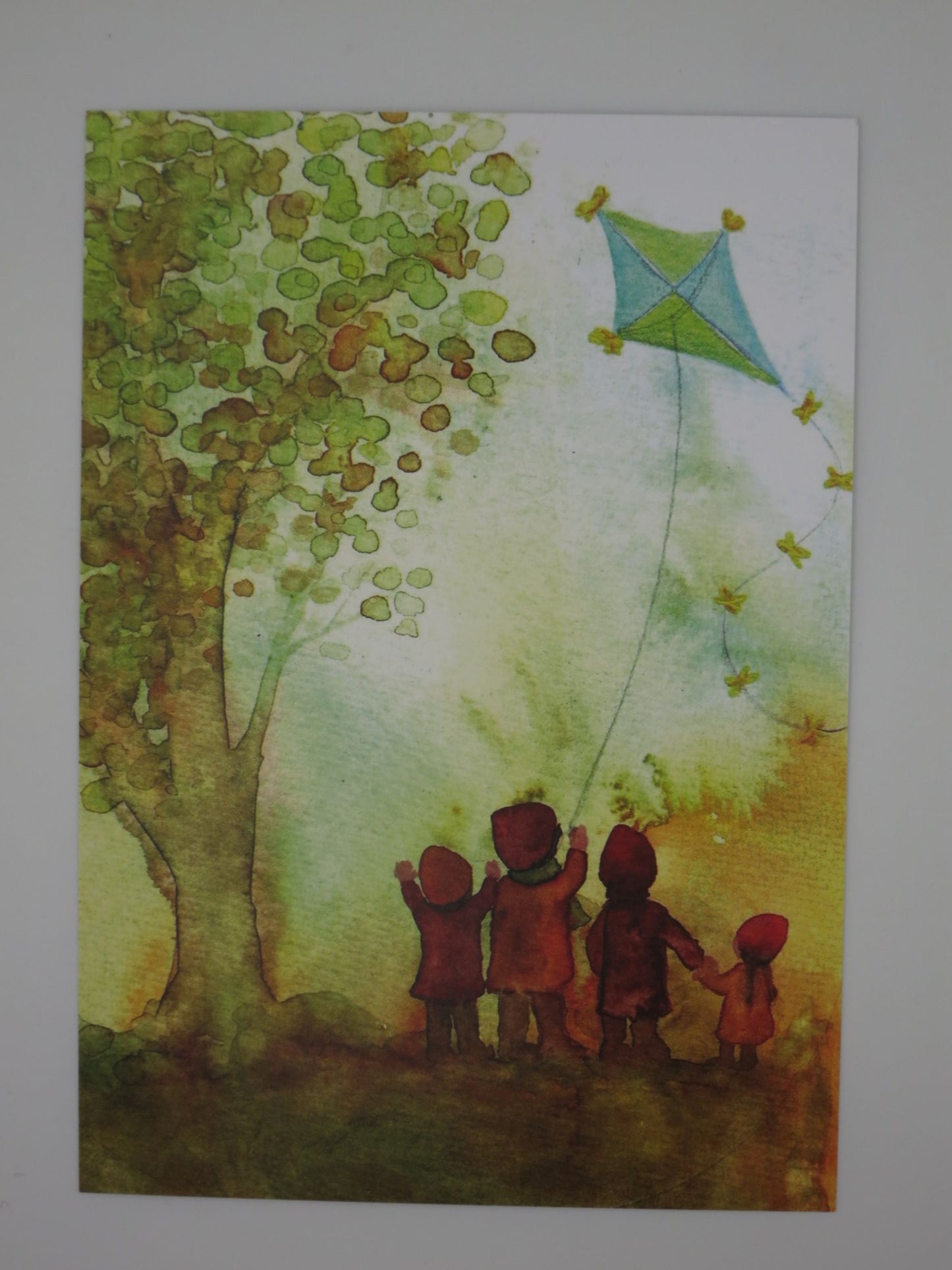 Herbst Postkarte Kinder mit Flugdrachen PKHE160: vier Kinder schauen blau-gruenem Drachen hinterher, Aquarell von Anna Hunold