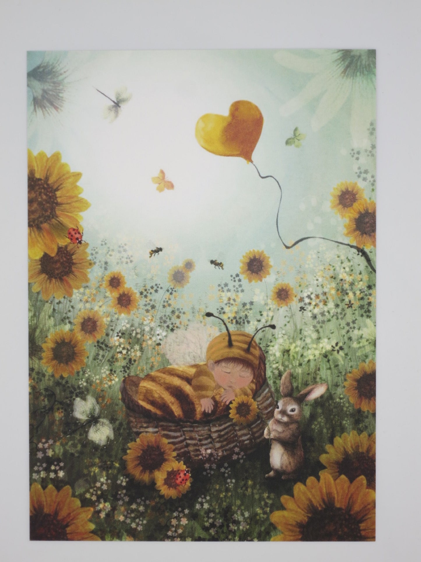 Postkarte Kleine Honigbiene: schlafendes Baby im Bienenkostüm zwischen Sonnenblumen, Illustration von Bijdehansje