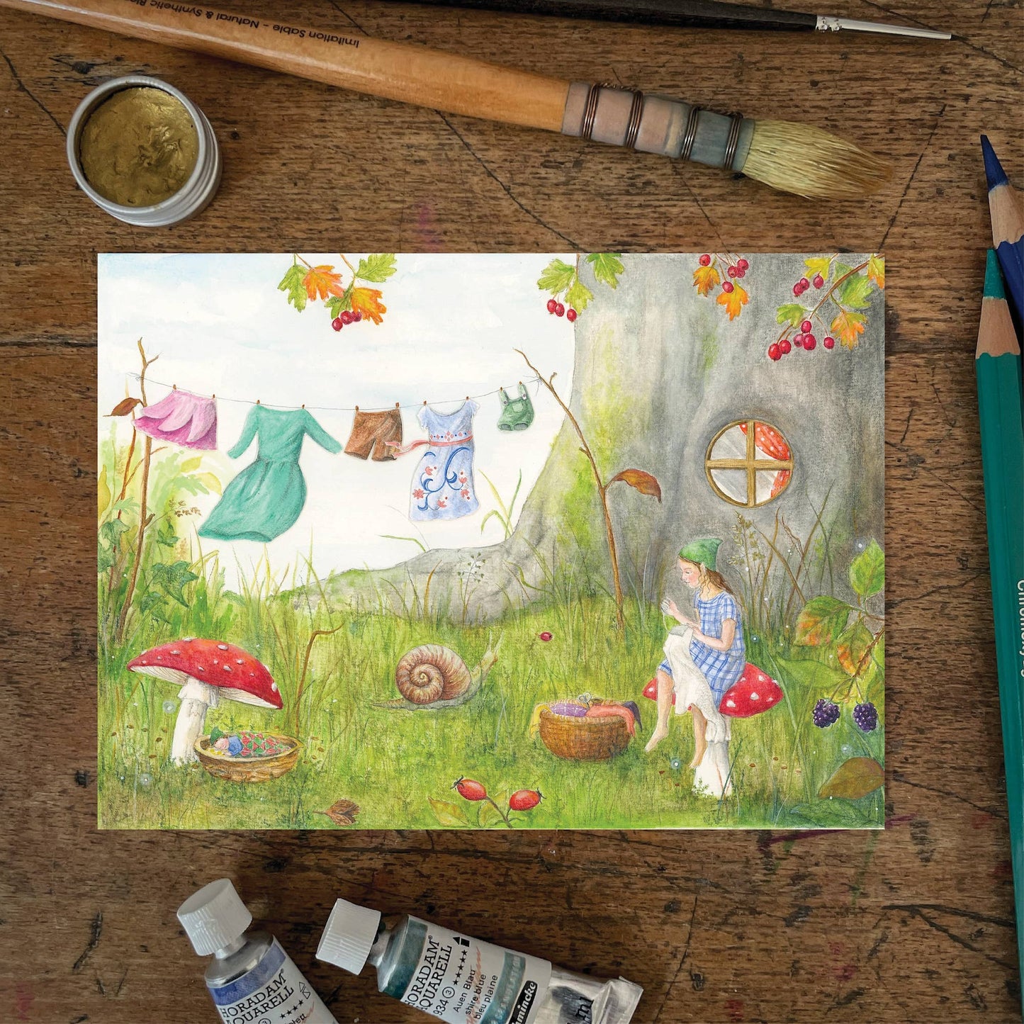 Herbst Postkarte Waschtag PKHE241: Elfe vor Baumhaus mit Waescheleine im Garten mit Schnecke Fliegenpilzen Baby und Herbstzweigen