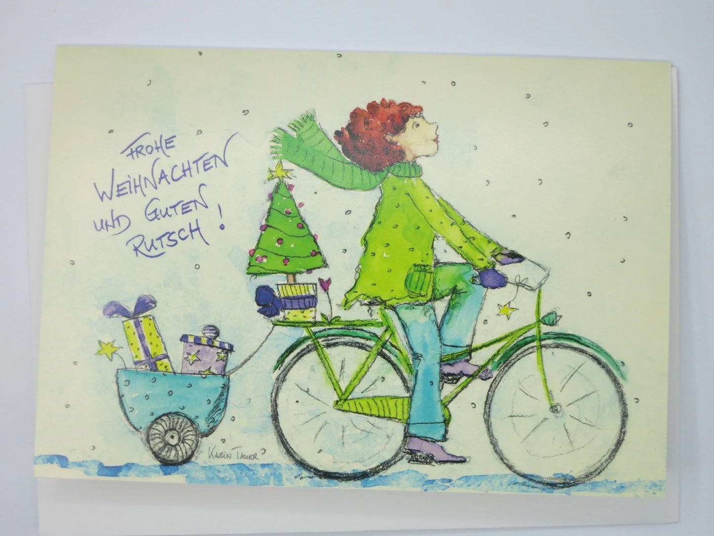 Weihnachtskarte mit Umschlag 'Frohe Weihnachten und einen guten Rutsch' von Karin Tauer: Person auf dem Fahrrad transportiert Weihnachtsbaum und Geschenke im Anhänger.