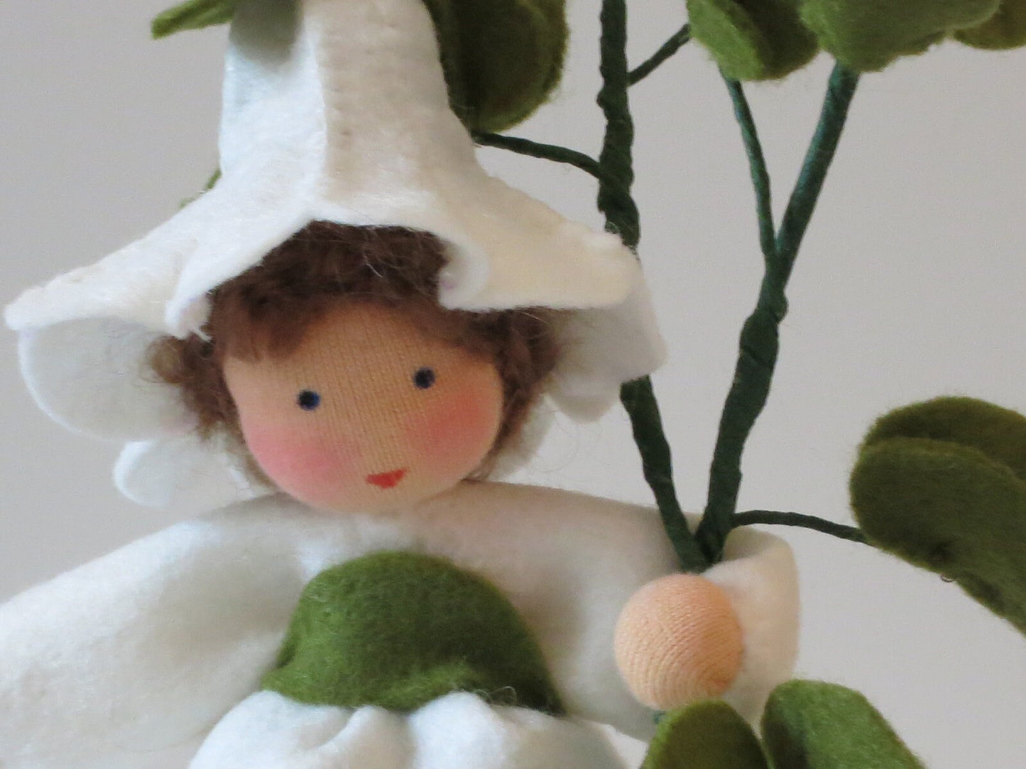 Detailaufnahme des handgefertigten Ackerwinde-Blumenkinds mit weißem Blütenhut und grünem Blütenzweig, Art. FR7.