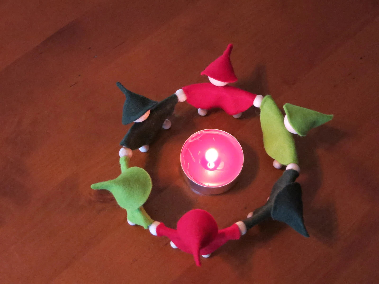 Adventszwergenkreis aus rotem und grünem Filz mit Teelicht, von oben fotografiert für den Waldorf Jahreszeitentisch.