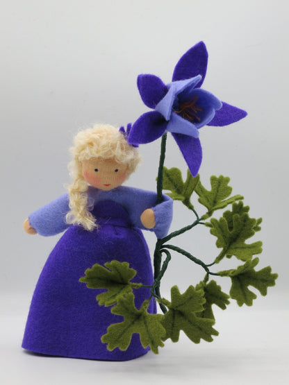 Akelei-Blumenkind mit großer violetter Filzblüte und verzweigtem grünem Blattwerk als Frühlingsdeko.
