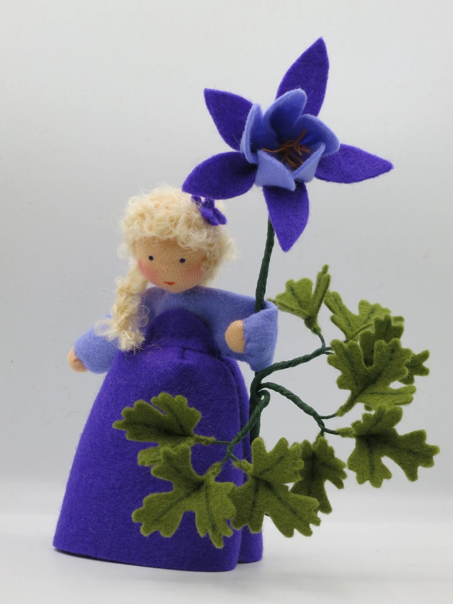 Frontalansicht des Akelei-Blumenkinds mit violetter Blüte und grünem Filzlaub für den Jahreszeitentisch.