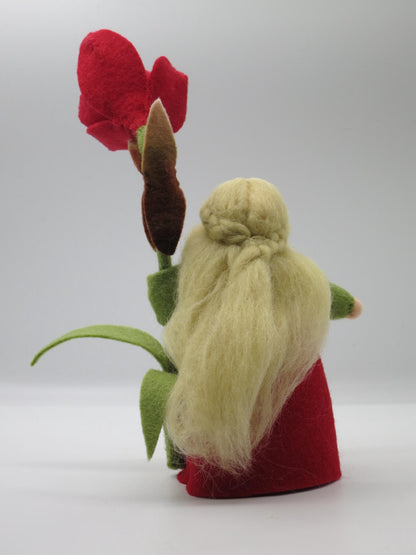 Rückansicht des Amaryllis-Blumenkinds mit langem blondem Wollhaar, rotem Filzkleid und Blütenstiel.
