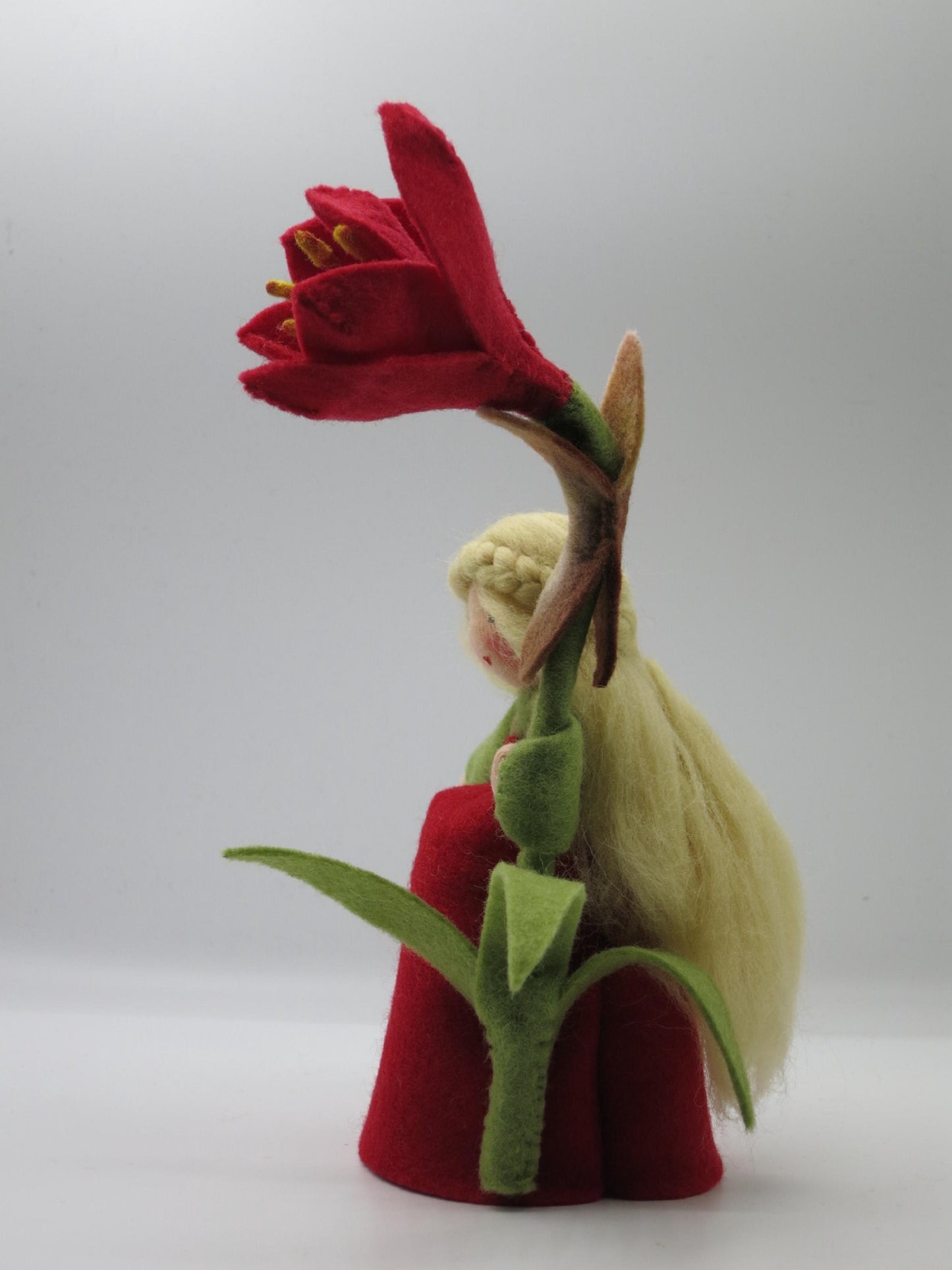 Seitenansicht des Amaryllis-Blumenkinds mit langem blondem Wollhaar und dunkelroter Filzblüte, Art. WI30.