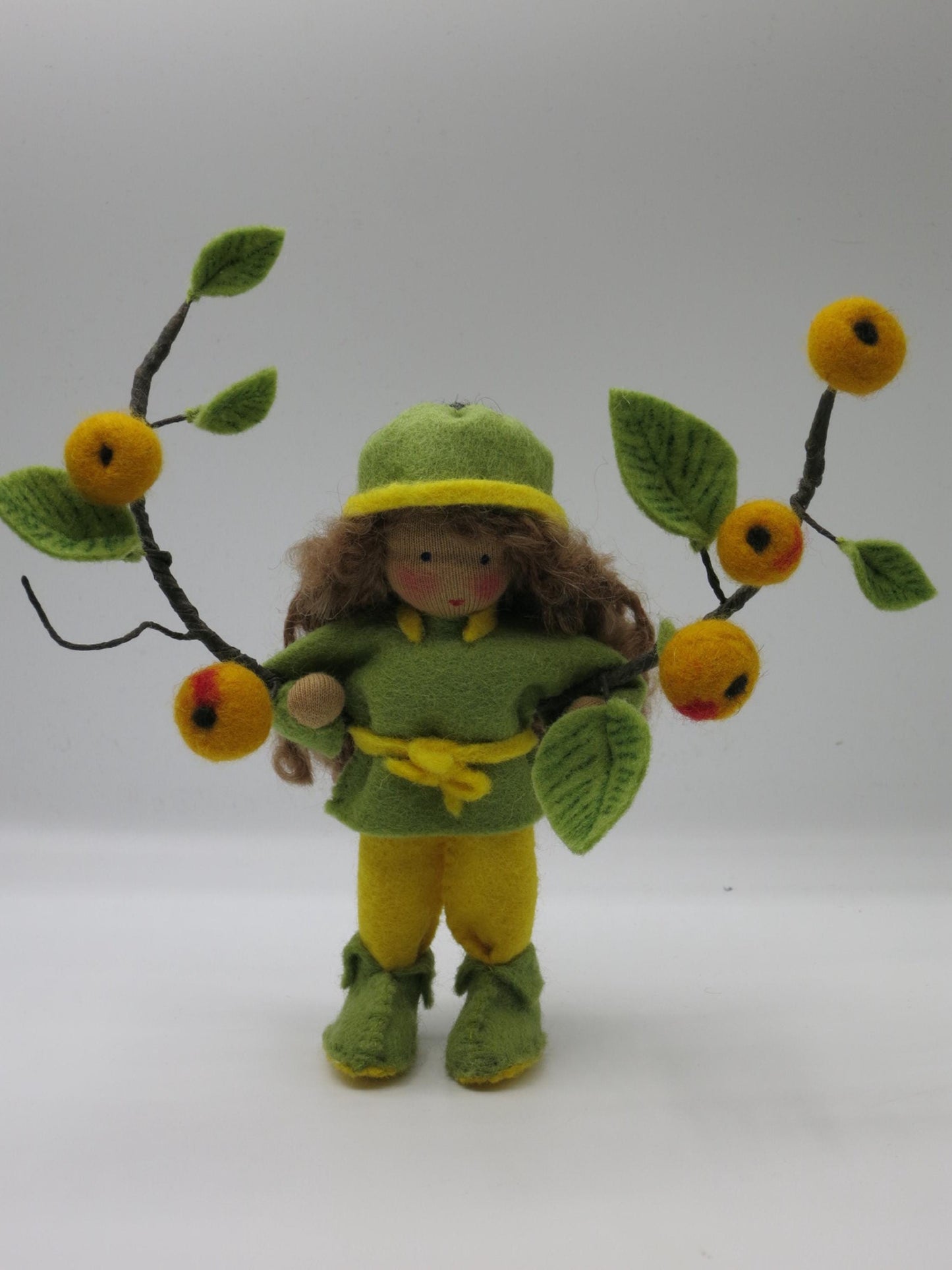 Handgefertigtes Apfelkind in Grün und Gelb mit braunem Wollhaar und Apfelzweigen für den Herbst-Jahreszeitentisch.