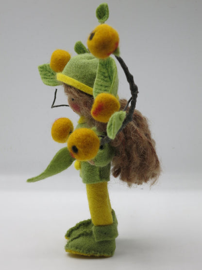 Seitenansicht des Apfelkinds in Grün und Gelb mit braunem Wollhaar und einem Zweig voller Filzäpfel.