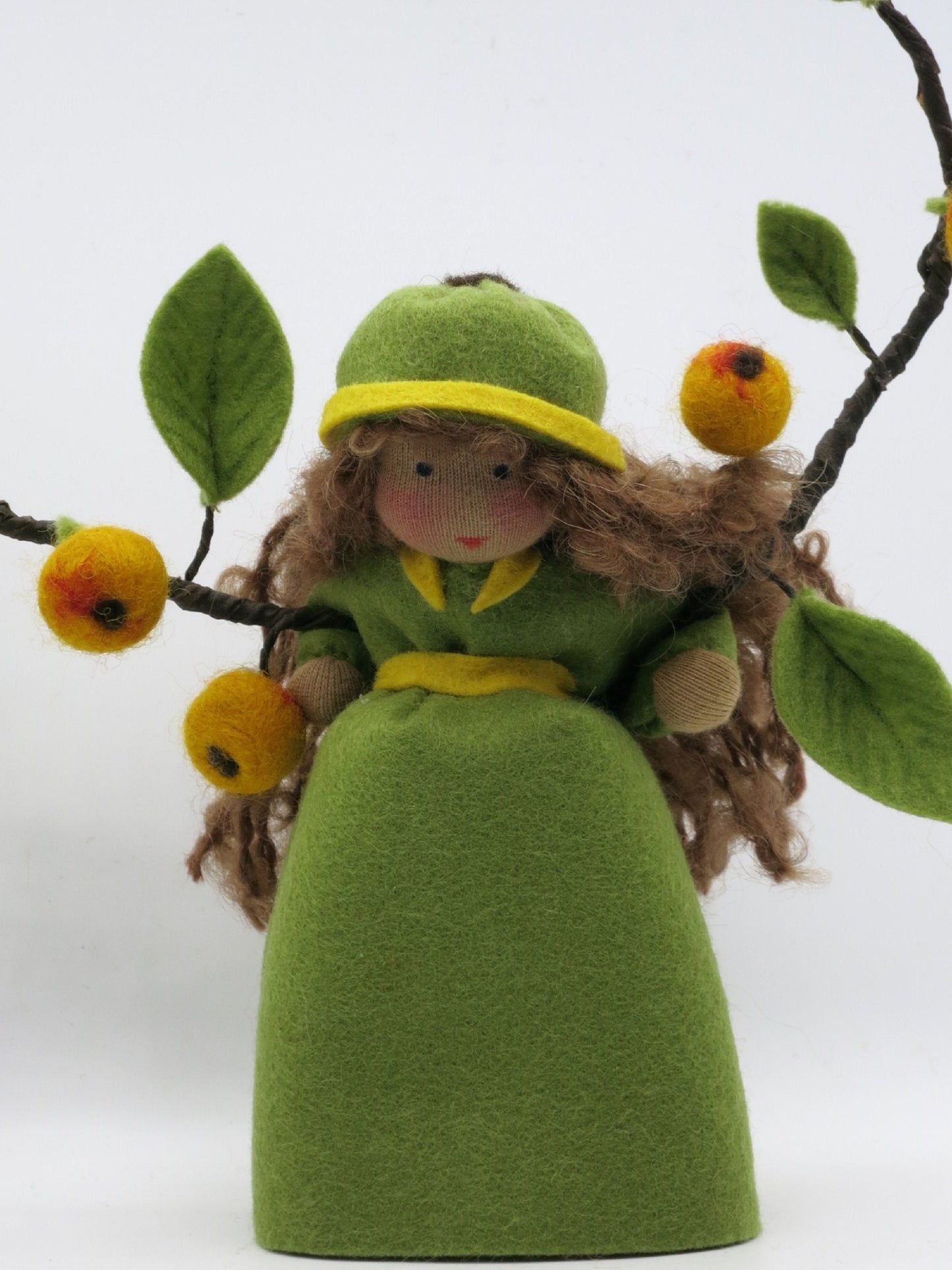 Vorderansicht des Apfelkinds mit braunem Wollhaar, grünem Filzkleid und gelben Äpfeln für den Jahreszeitentisch.
