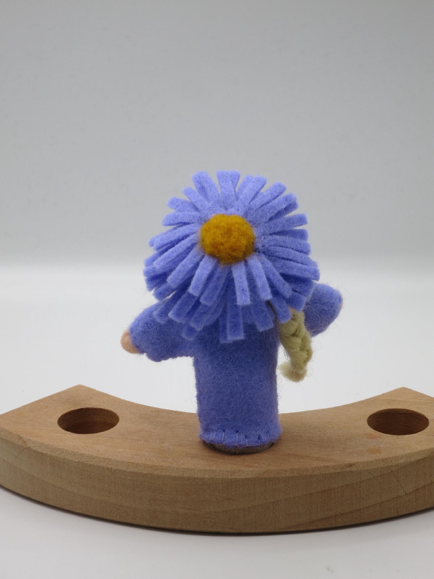 Rückansicht des violetten Aster-Blumenkinds Art. HE54 mit großer Filz-Aster als Blütenhaube auf dem Holzring.