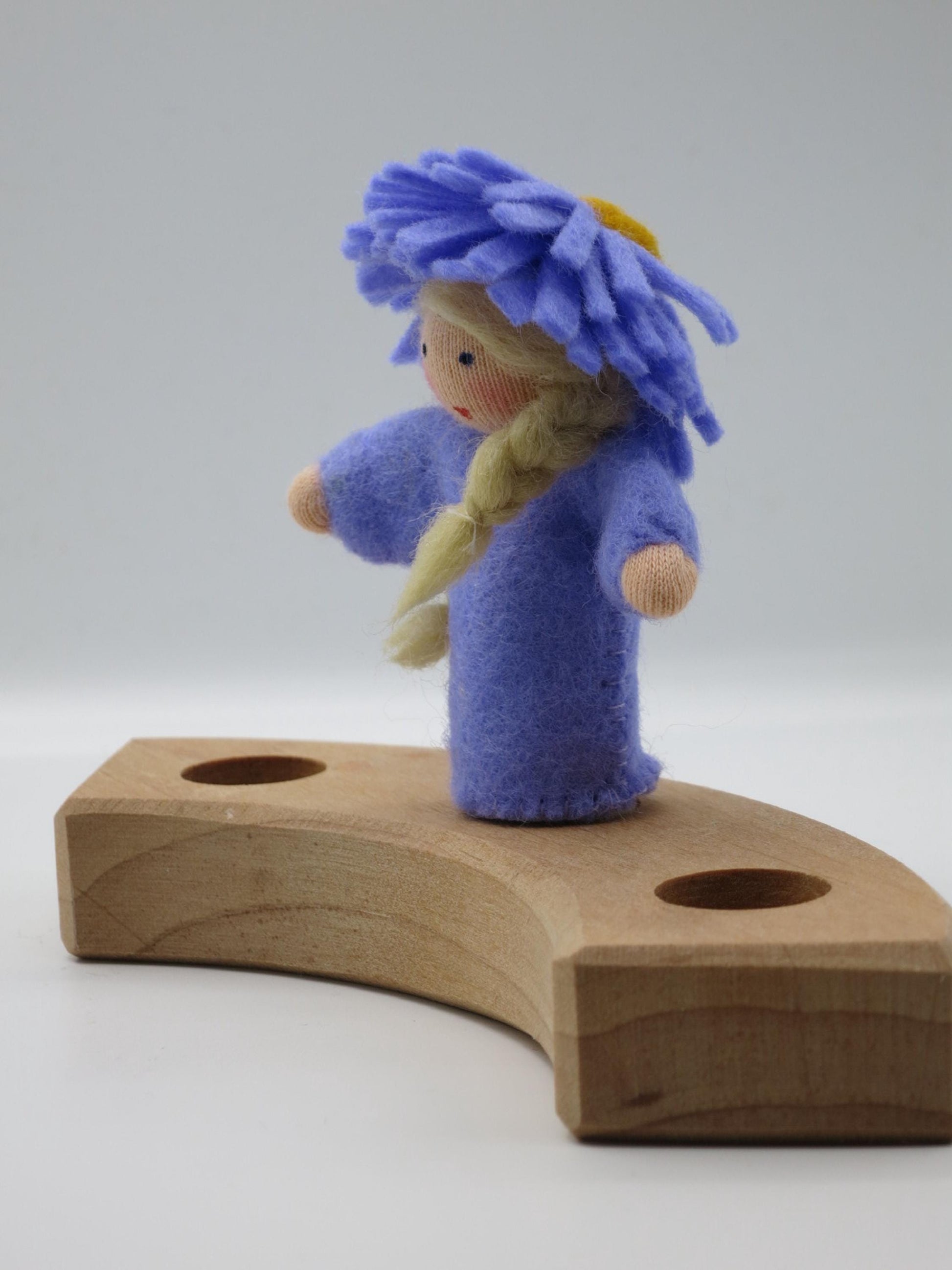Seitenansicht des violetten Aster-Blumenkinds Art. HE54 mit blondem Zopf auf einem Holz-Geburtstagsring.