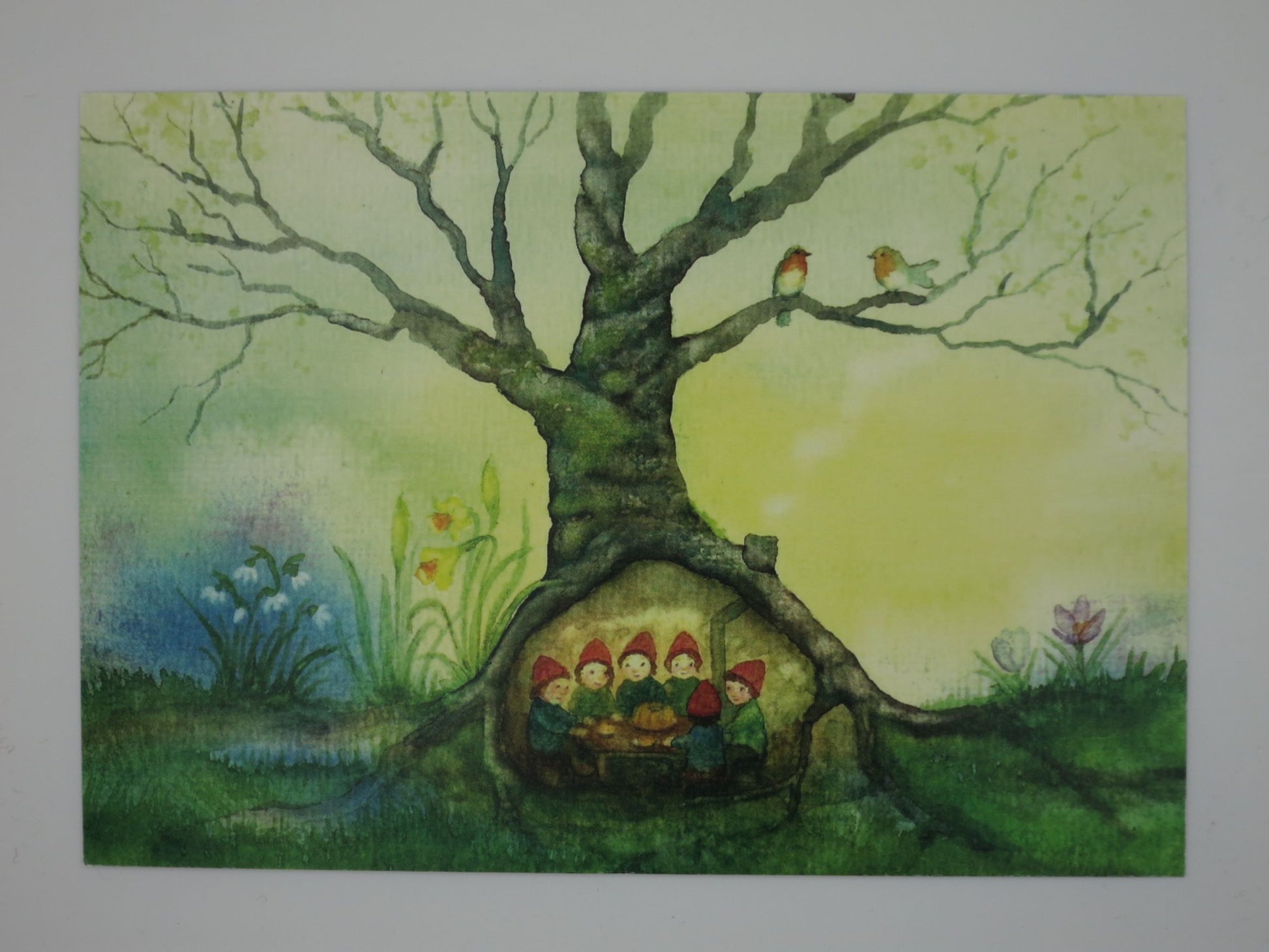 Postkarte Baumhoehle von Anna Hunold, Zwerge feiern in Baumhoehle mit Schneegloeckchen und Krokus