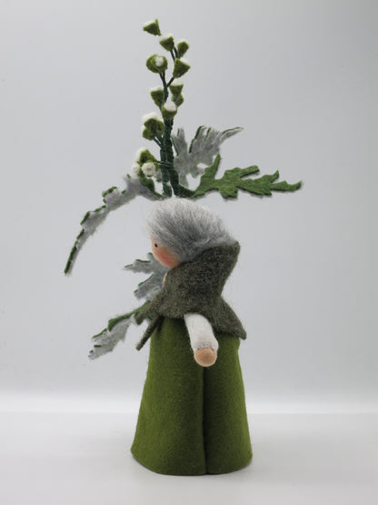 Rückansicht des Beifuß-Blumenkinds Art. SO16 mit grauem Wollhaar, dunkelgrünem Umhang und hohem Beifußzweig.