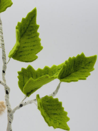 Detailaufnahme grüner Birkenblätter aus Filz an einem weiß-schwarz gestalteten Birkenzweig des Baumkinds Art. FR22.