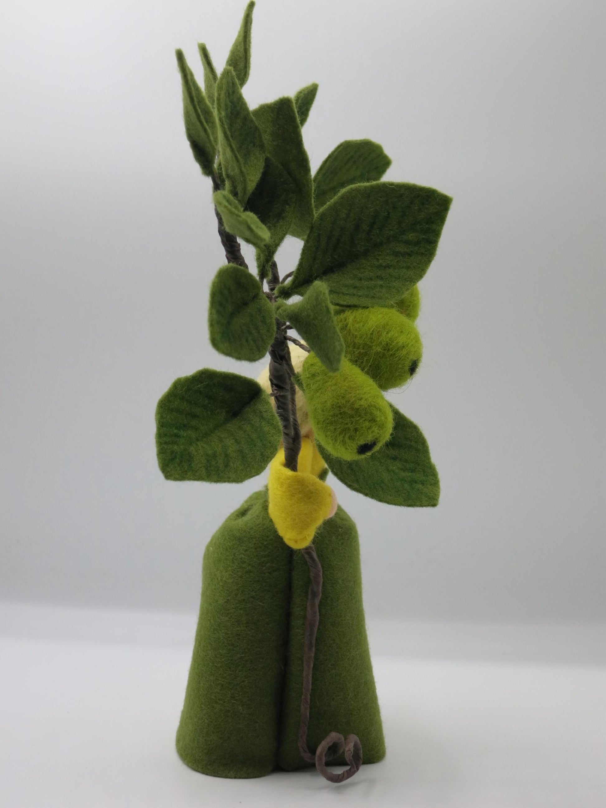 Rückseite des Birnen-Blumenkinds mit grünem Filzkleid und dichtem Zweig aus Birnen und Blättern aus Wollfilz.