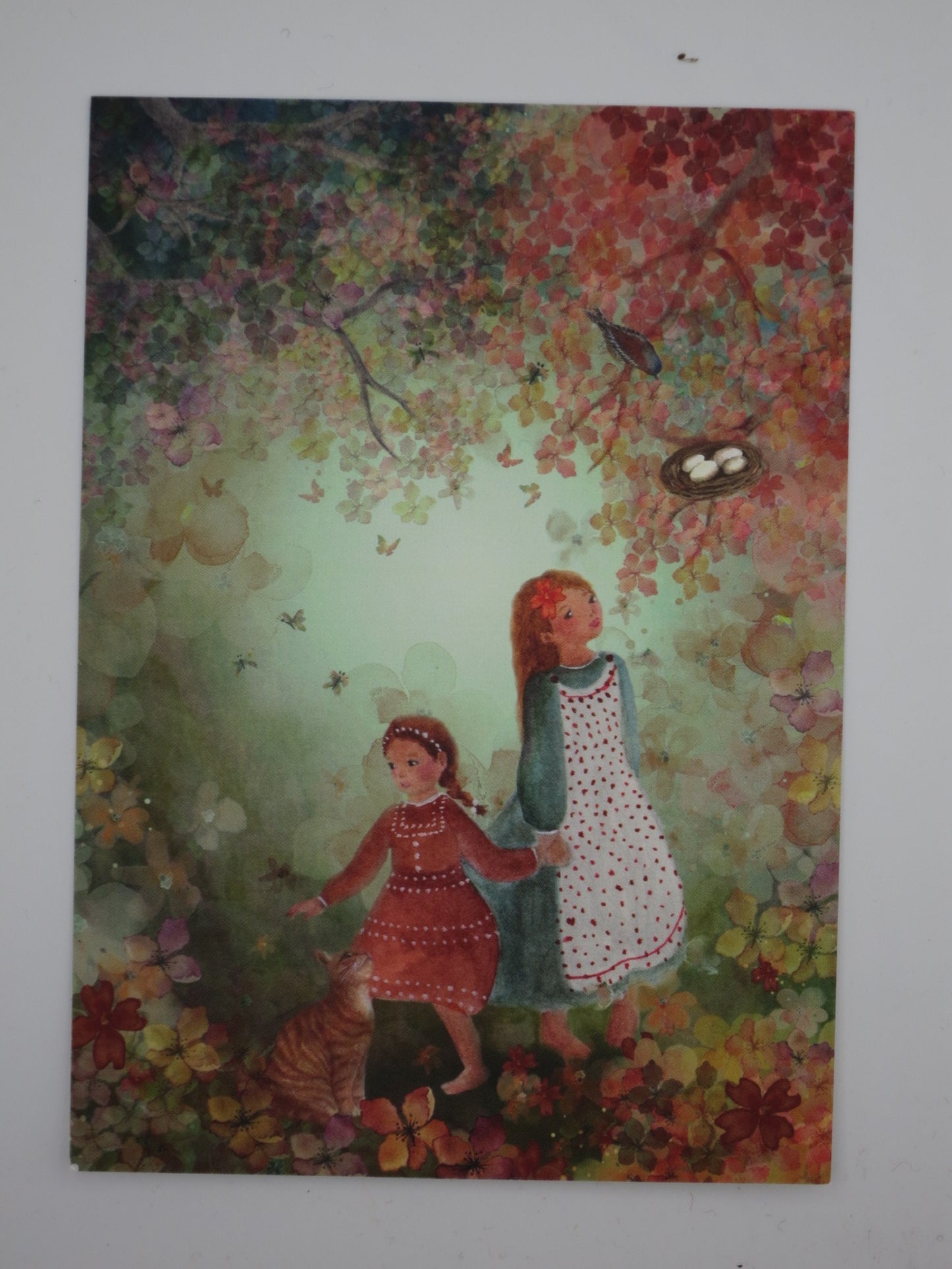 Postkarte Blütenphantasie von Bijdehansje mit zwei Mädchen, Katze und Rotkehlchen-Nest im Blütenmeer