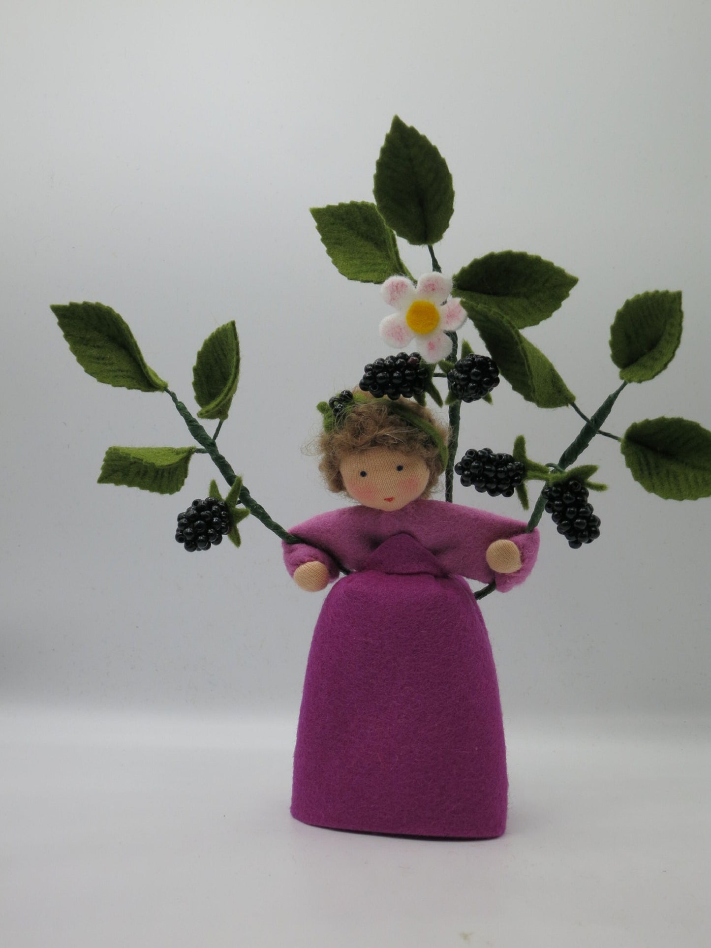Handgefertigtes Brombeer-Blumenkind mit violettem Filzkleid, weißen Blüten und verzweigtem Brombeerstrauch.