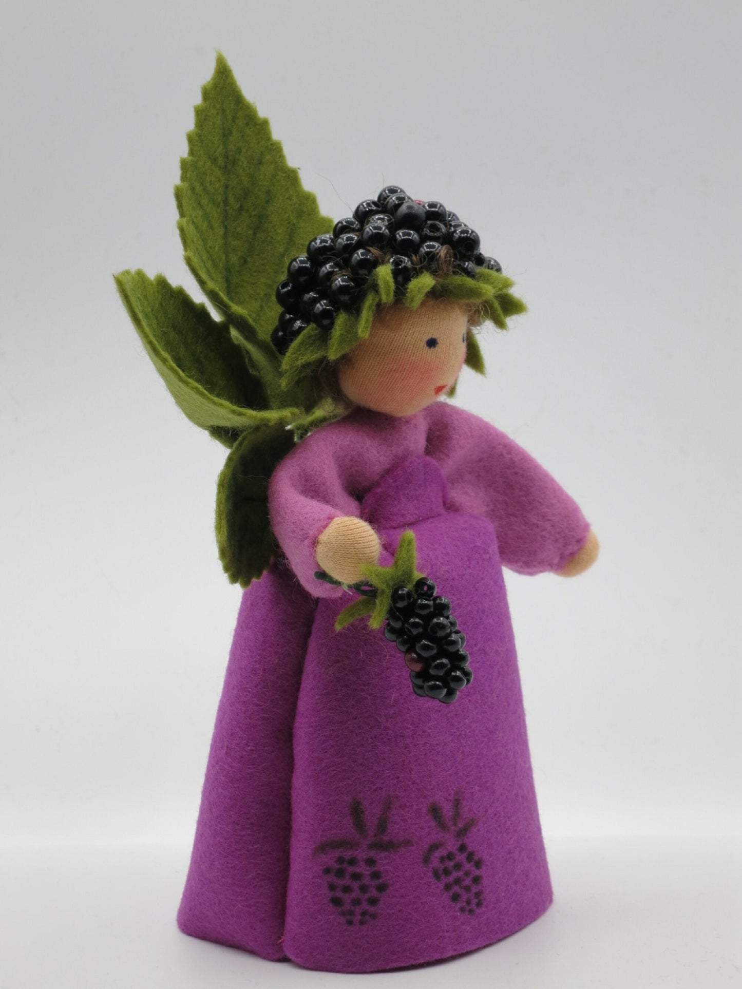 Dreiviertelansicht des Brombeer-Elfchens mit Brombeerkranz, Beerenzweig und gestickten Brombeeren am violetten Filzkleid.