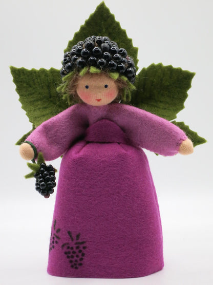 Vorderansicht des Brombeer-Elfchens mit violettem Filzkleid, gesticktem Brombeermotiv und Brombeerzweig in der Hand.
