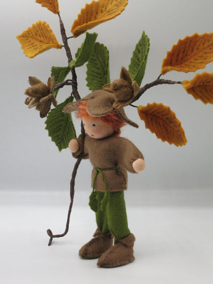 Dreiviertelansicht des Bucheckern-Jungen mit brauner Tunika, grüner Hose, Filzstiefeln und herbstlichem Buchenzweig.