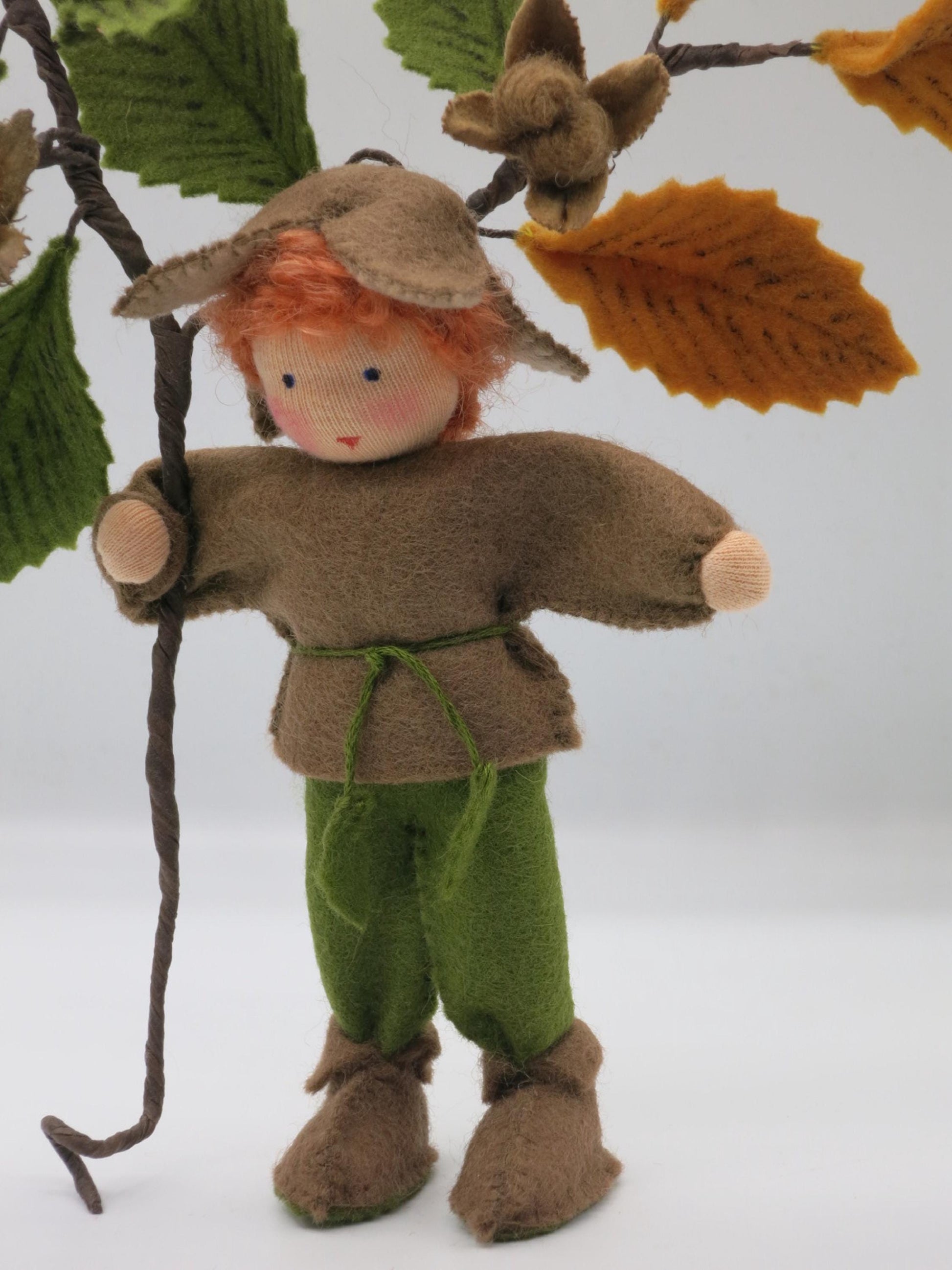 Gesamtfigur des Bucheckern-Jungen in braun-grüner Filzkleidung mit Stiefeln und langem handgefertigtem Buchenzweig.