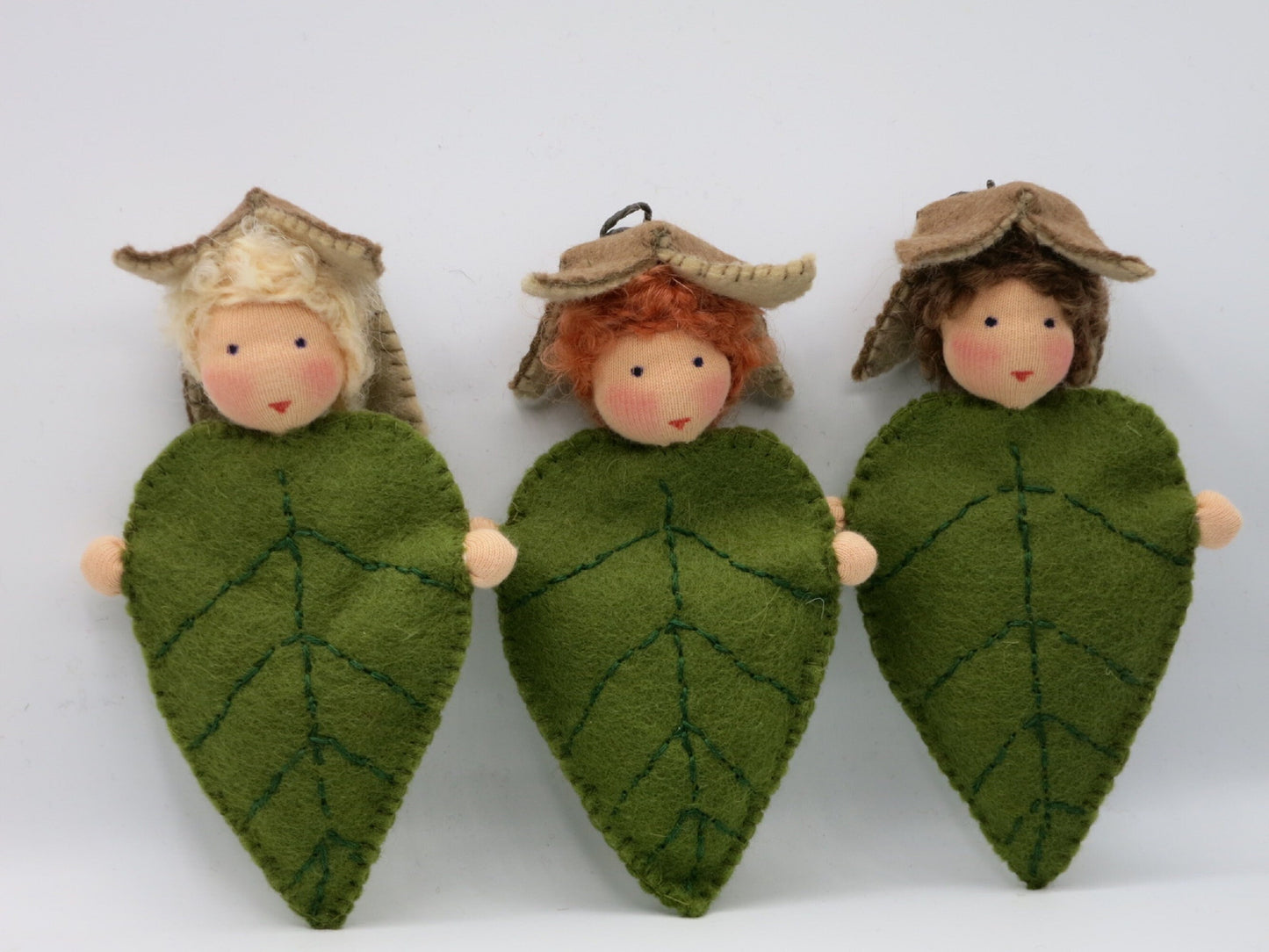 Drei handgefertigte Buchenblätter-Kinder mit grünen Filzblättern und Bucheckern-Hüten für den Jahreszeitentisch