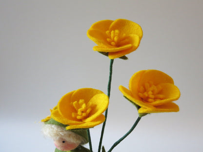 Nahaufnahme der drei gelben Butterblumen aus Filz über dem blonden Blumenkind mit grünem Hut