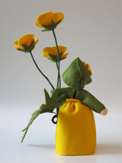 Rückansicht des Butterblumen-Blumenkinds mit gelbem Filzkleid, grünem Blätterkragen und drei Blütenstielen