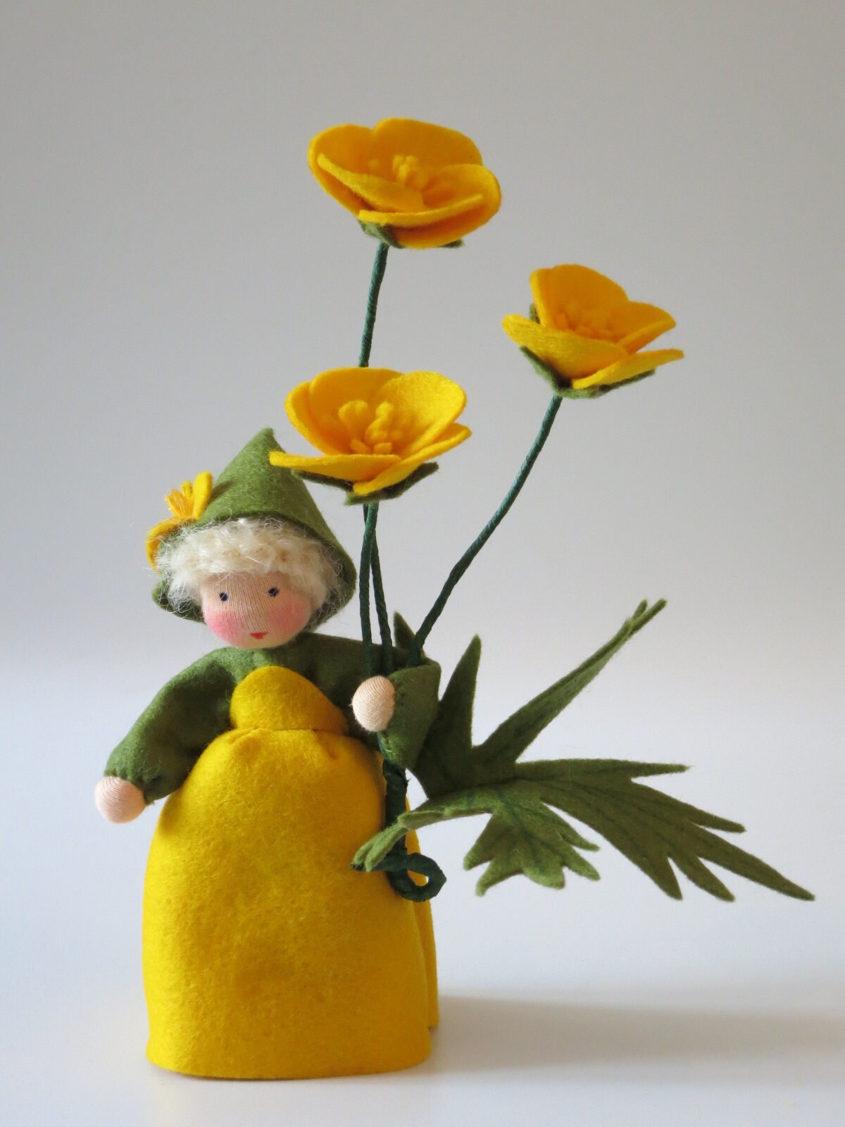 Handgefertigtes Butterblumen-Blumenkind mit gelbem Filzkleid, drei Blüten und großem grünen Blatt für Waldorf-Dekoration