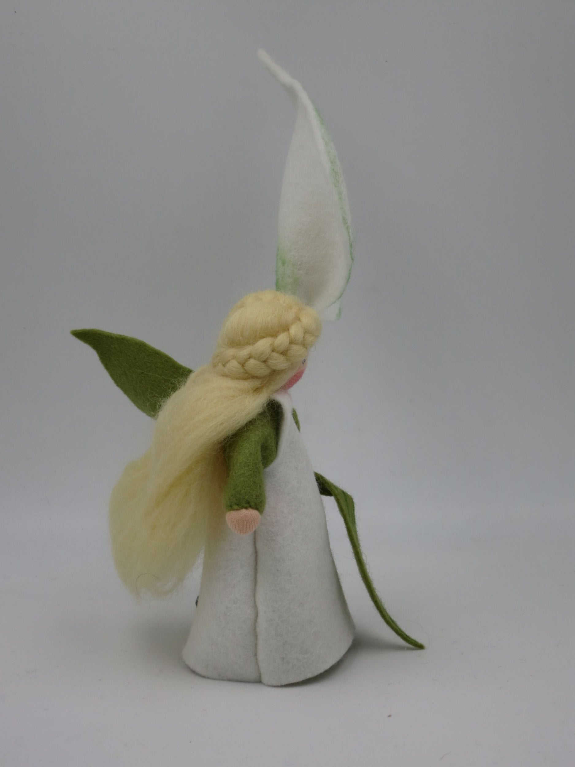 Calla-Blumenkind im Profil mit weißem Filzkleid, grünen Ärmeln, langem Blondhaar und hoher Blütenhaube