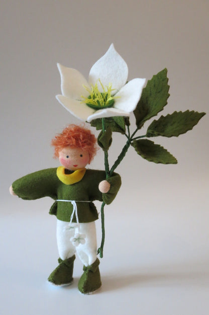 Christrosen-Blumenkind als Junge mit roten Haaren, grün-weißer Filzkleidung und großer weißer Winterblüte