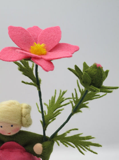 Detail einer rosa Schmuckkörbchen-Blüte aus Filz mit gelber Mitte, grüner Knospe und feinen Blättern
