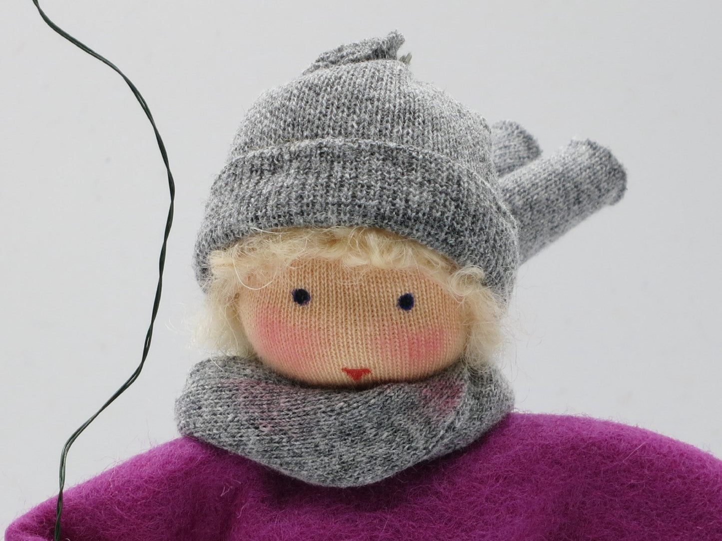 Porträt des Drachenkindes mit blondem Haar, grauer Wollmütze, gestricktem Schal und violettem Filzoberteil