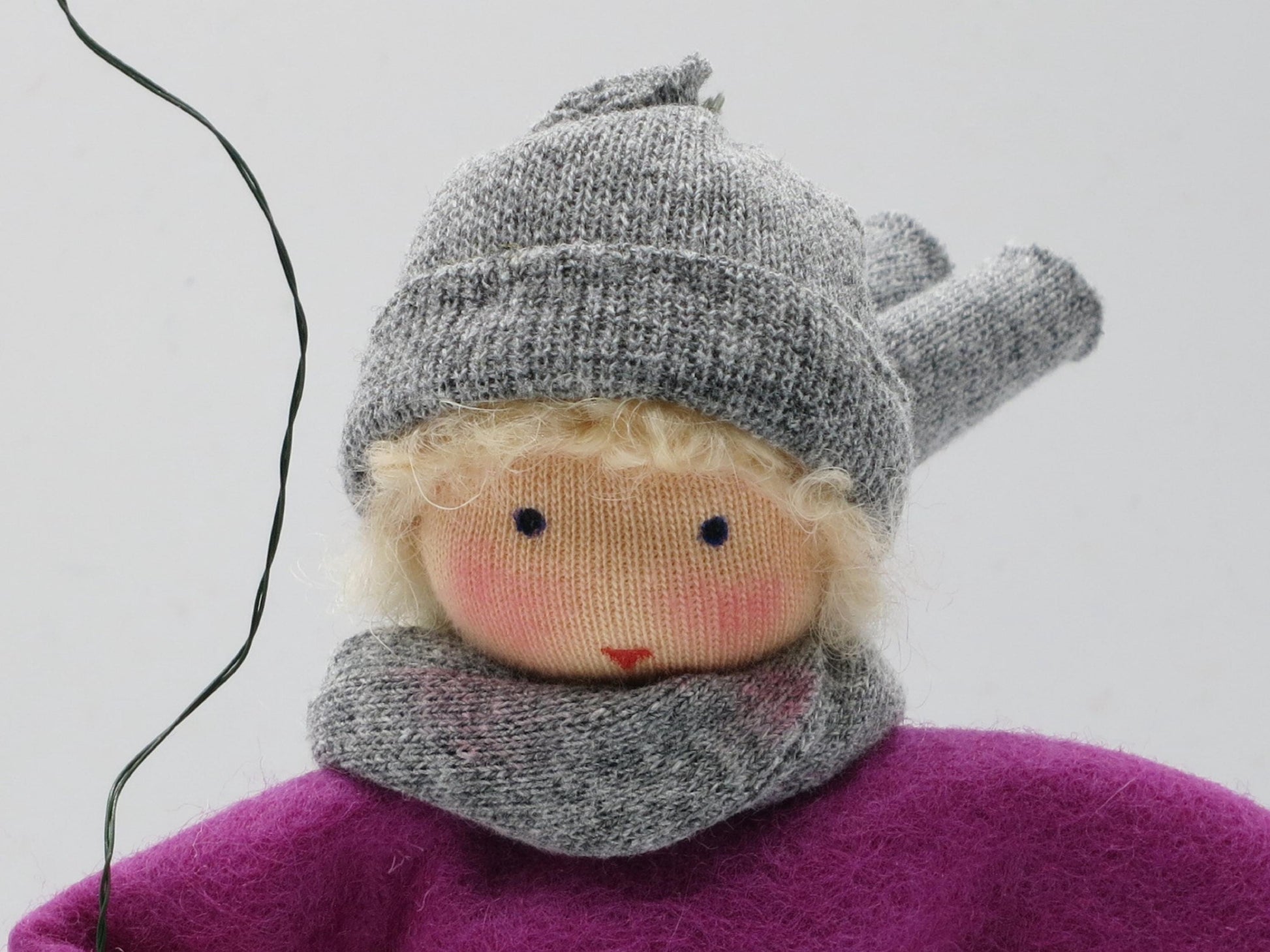 Porträt des Drachenkindes mit blondem Haar, grauer Wollmütze, gestricktem Schal und violettem Filzoberteil
