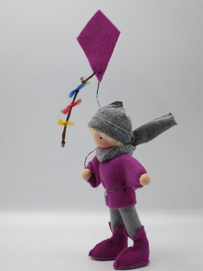 Seitliche Ansicht des Drachenkindes mit violettem Winddrachen, buntem Schweif und grau-lila Filzkleidung