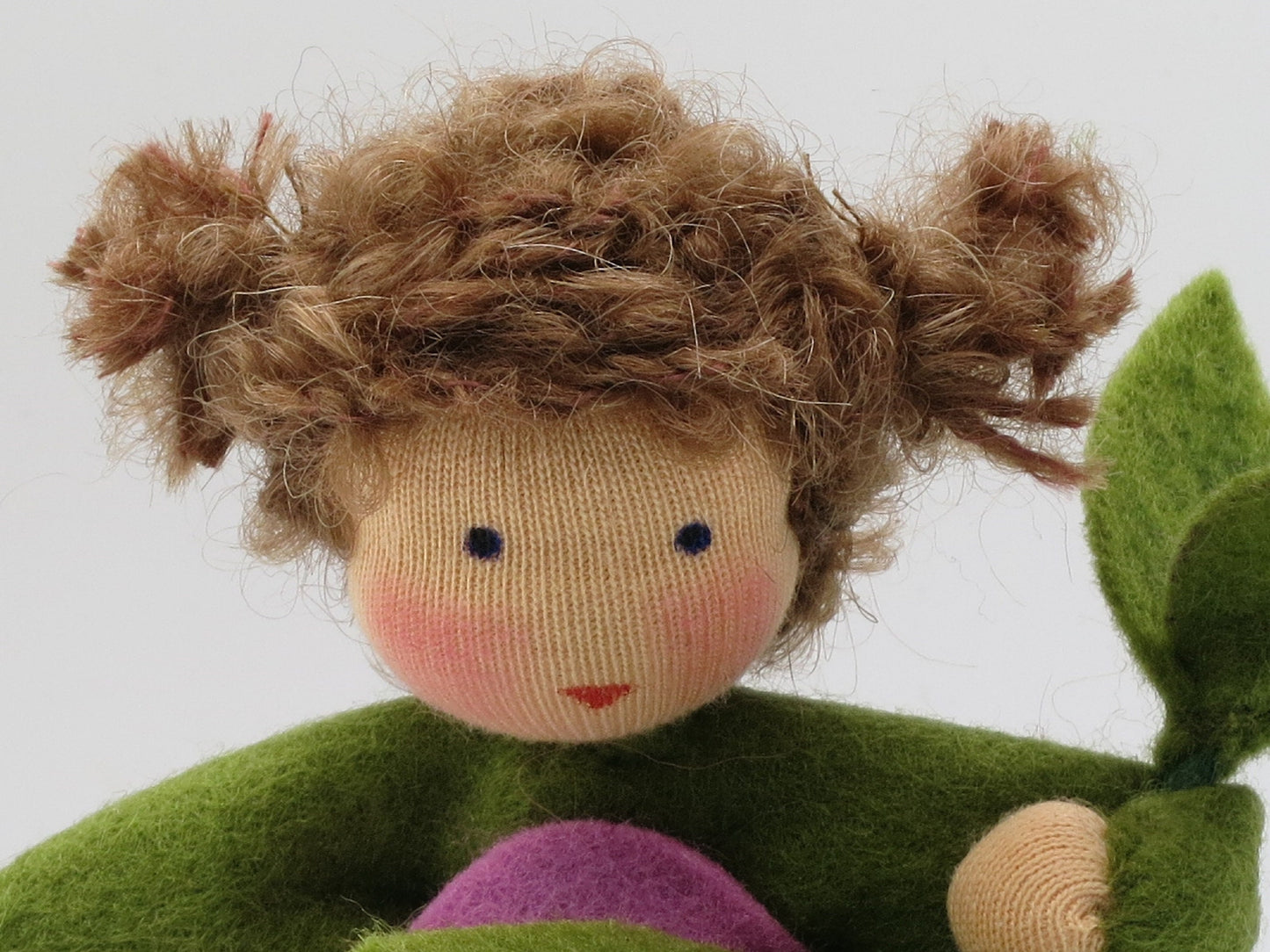 Detailaufnahme des Duftwicken-Blumenkindes mit braunen Locken, handbemaltem Gesicht und grünem Filzoberteil