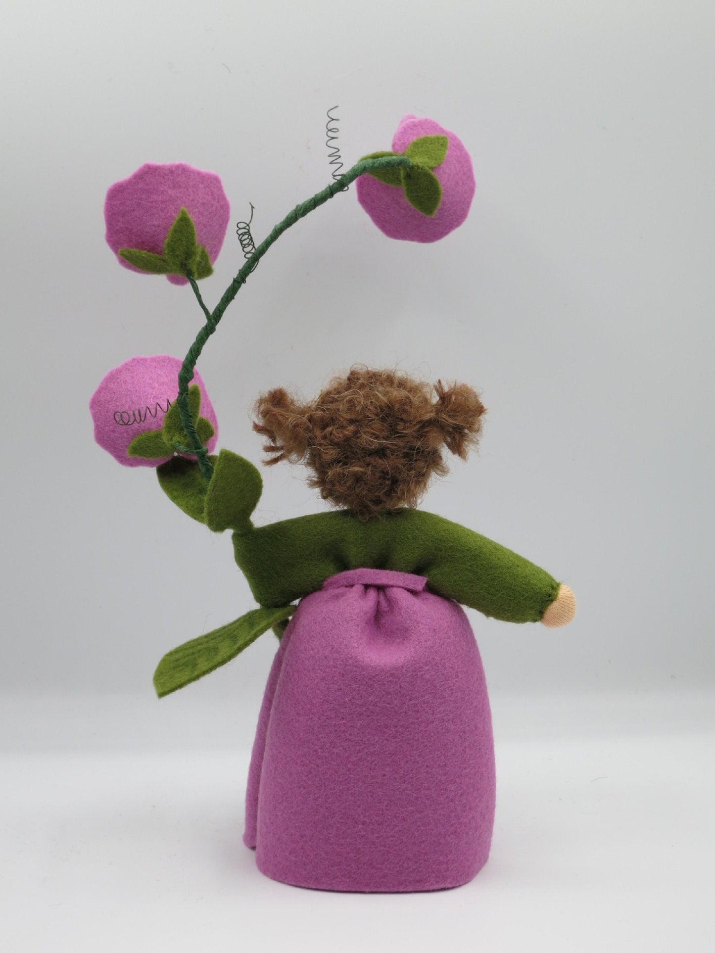 Rückansicht des handgefertigten Duftwicken-Blumenkindes mit lila Kleid, grünen Blättern und Blütenranke