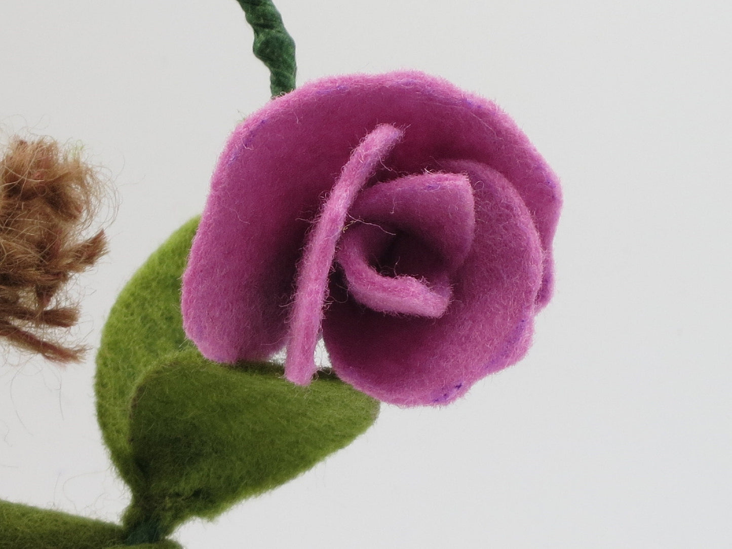 Nahaufnahme einer lila Duftwickenblüte aus Filz mit grünem Blatt am handgefertigten Blumenkind