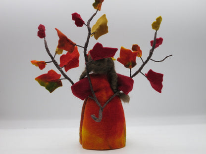 Rückansicht des handgefertigten Efeu-Blumenkindes mit braunem Haar, buntem Filzkleid und verzweigten Herbstblättern