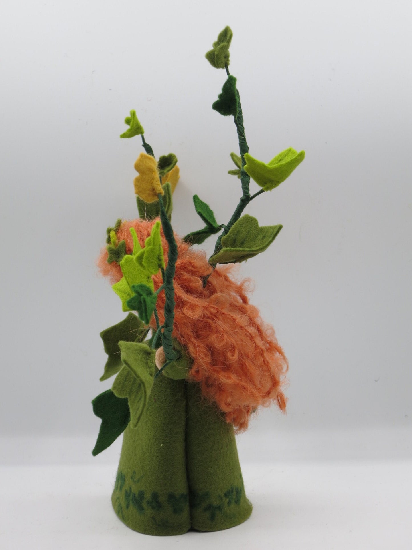 Seitenansicht des Efeu-Blumenkindes im grünen Filzkleid mit rotem Lockenhaar und hohen Blätterranken