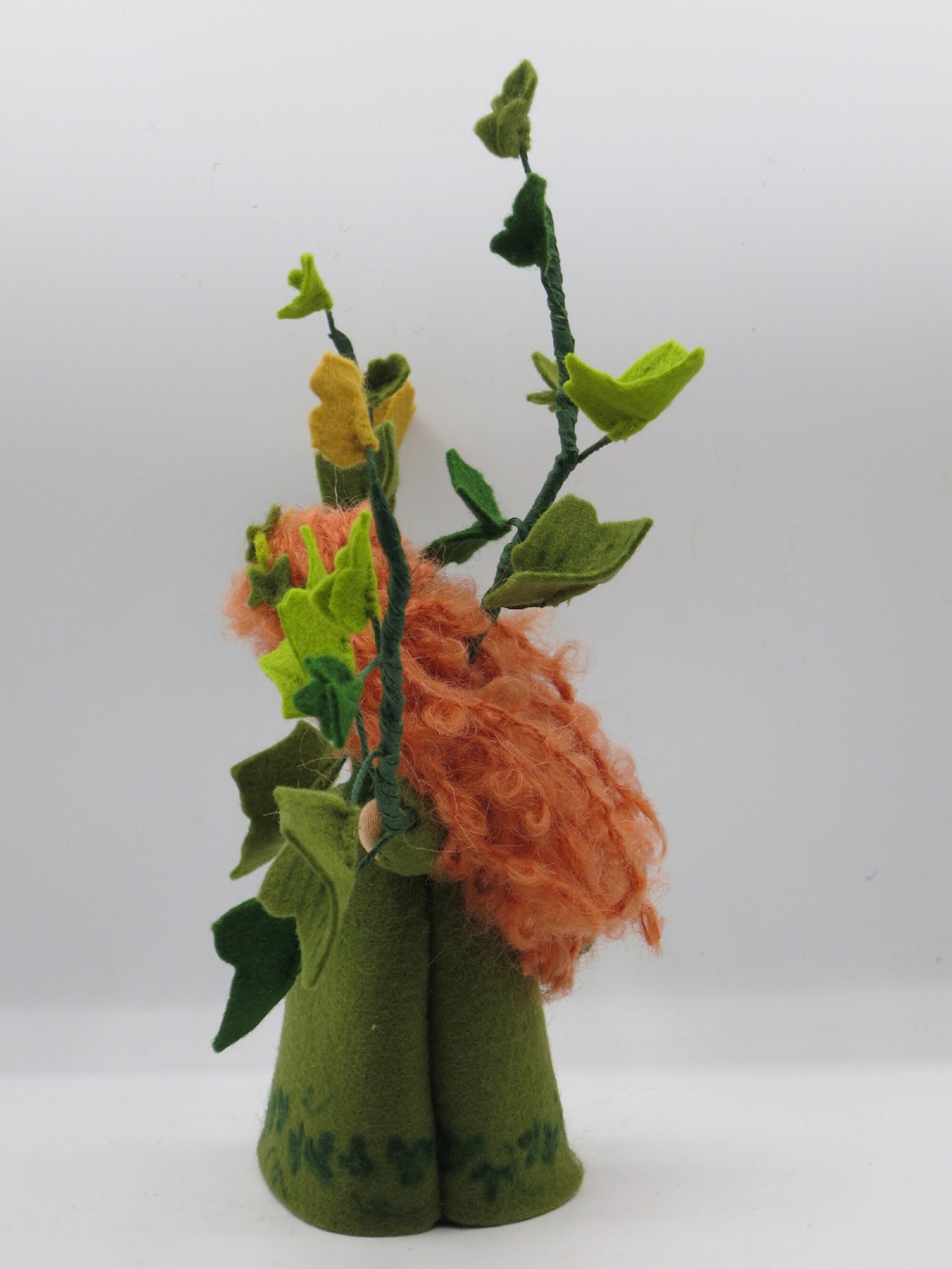 Seitenansicht des Efeu-Blumenkindes im grünen Filzkleid mit rotem Lockenhaar und hohen Blätterranken