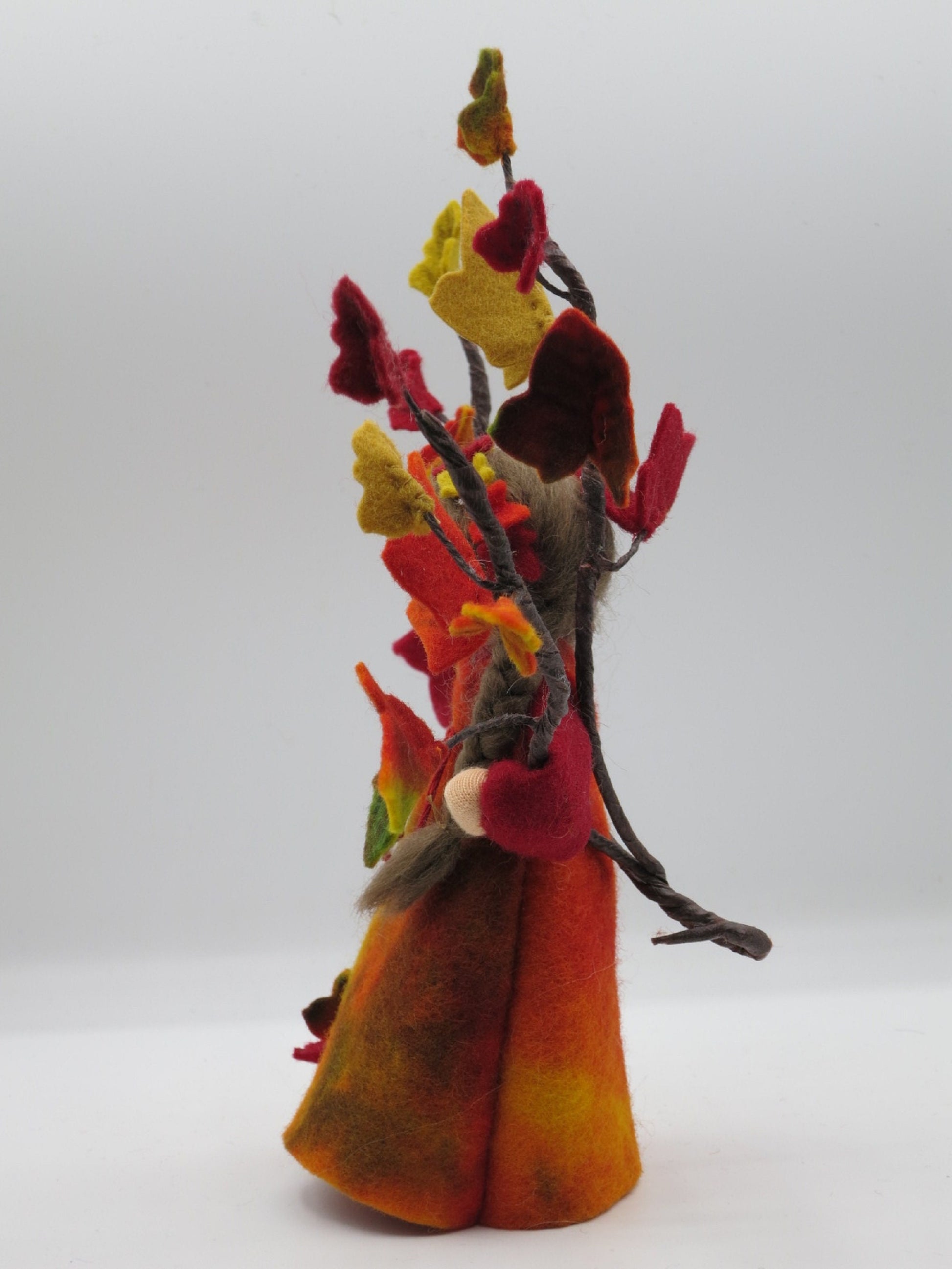 Seitenansicht des Efeu-Blumenkindes mit rot-gelbem Filzkleid und dichten Herbstlaub-Ranken für den Waldorf-Tisch