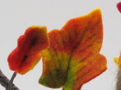 Nahaufnahme handgefertigter Efeublätter aus Filz in Rot, Orange und Grün am herbstlichen Blumenkind