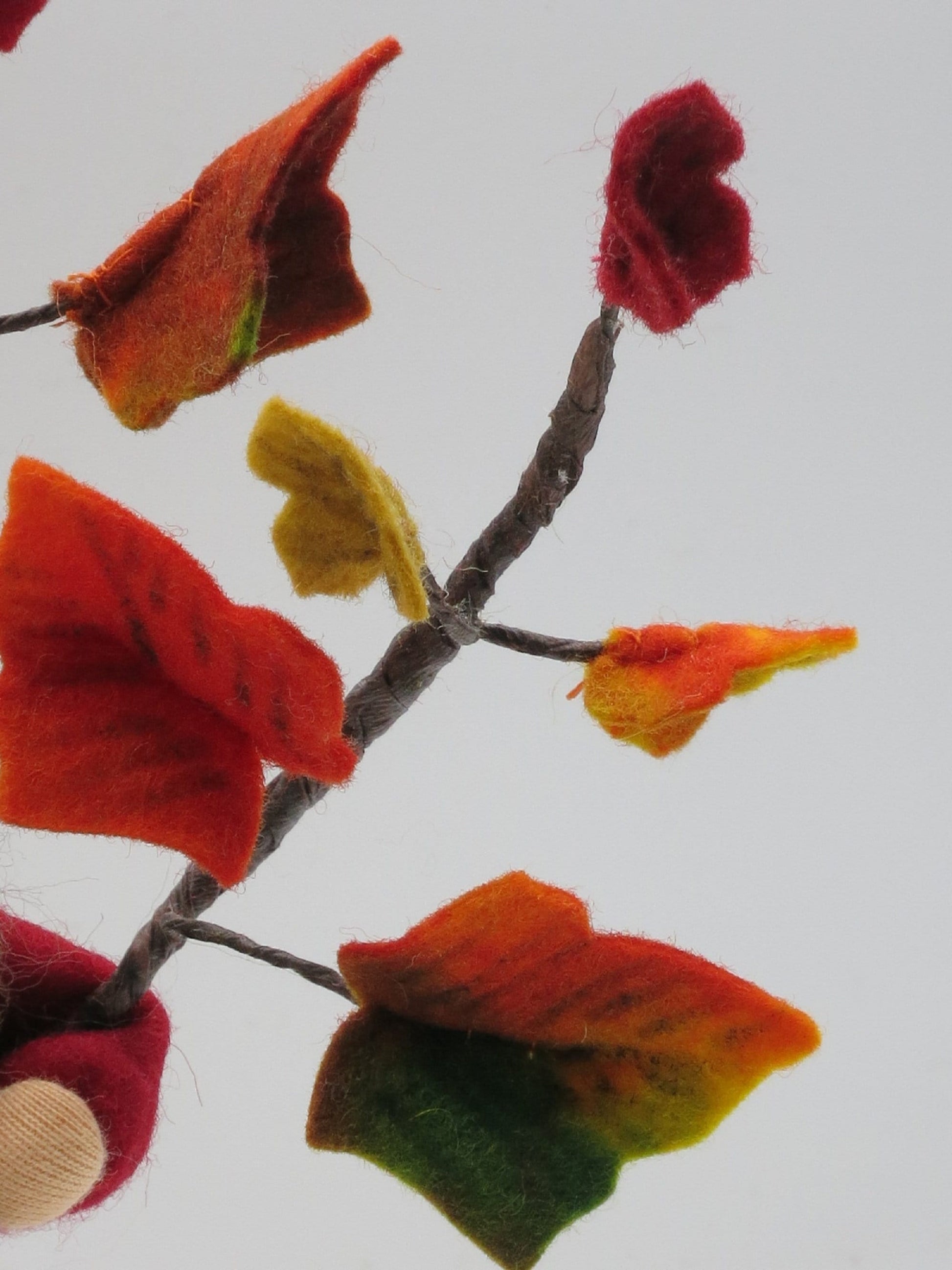 Detail einer handgefertigten Efeuranke mit roten, orangefarbenen, gelben und grünen Filzblättern im Herbst