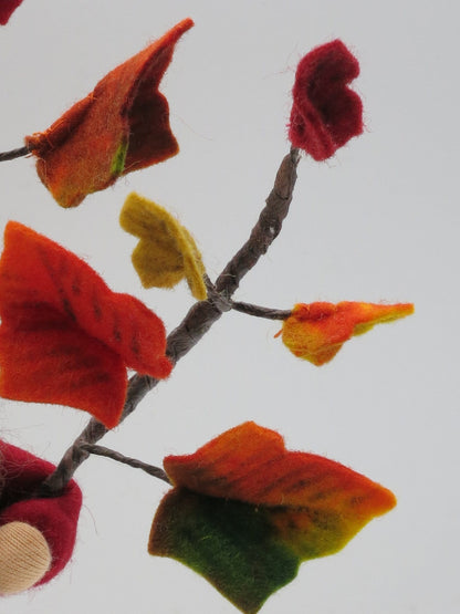 Detail einer handgefertigten Efeuranke mit roten, orangefarbenen, gelben und grünen Filzblättern im Herbst